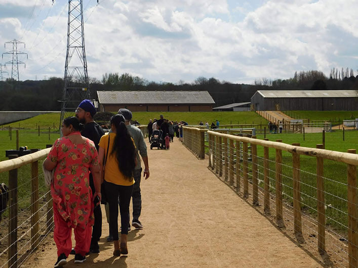 People walking on a path near a farm, surrounded by lush greenery and the beauty of nature.