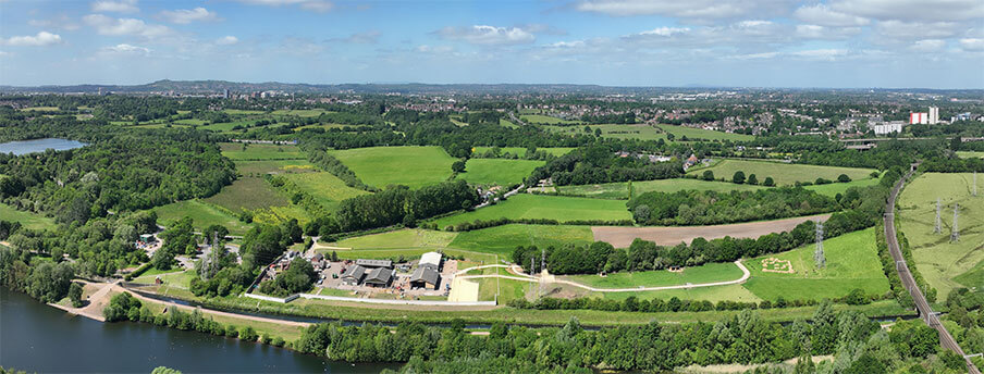Aerial view of a large green field and river with farm trail & interactions.